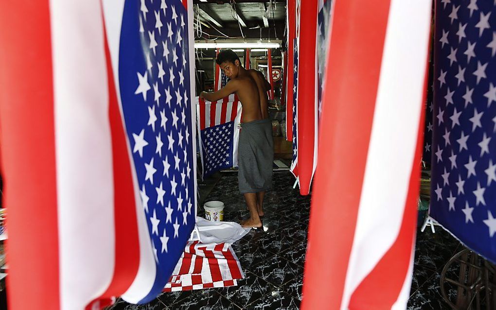 Een textielwerker is bezig met het verven van Amerikaanse vlaggen in Yangon. Foto EPA