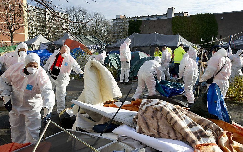 Schoonmakers ruimen de restanten van het tentenkamp van de asielzoekers in Amsterdam op.   Foto ANP