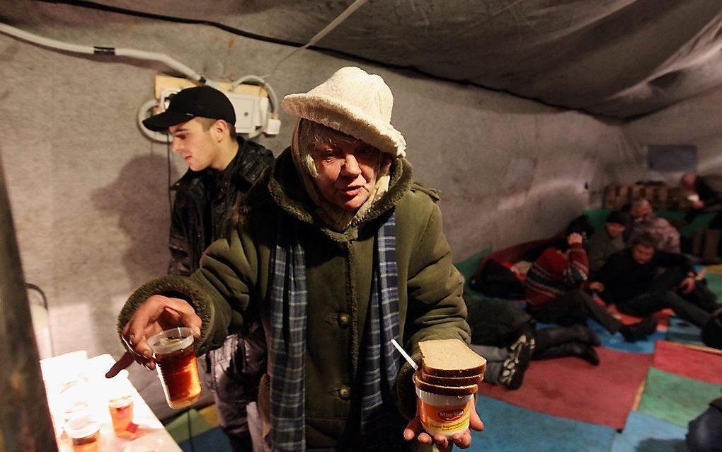 Een dakloze vrouw krijgt eten en drinken. Foto EPA