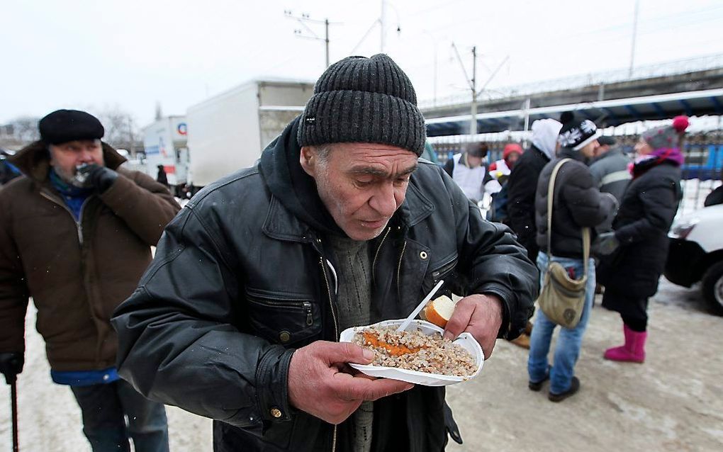 Een man in de Oekraïense hoofdstad Kiev geniet van een gratis maaltijd. Foto EPA