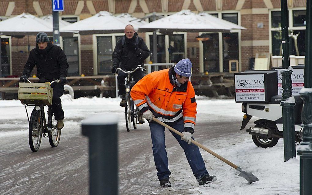 Een gemeentewerker ruimt sneeuw bij de Grote Markt in Haarlem.  Foto ANP