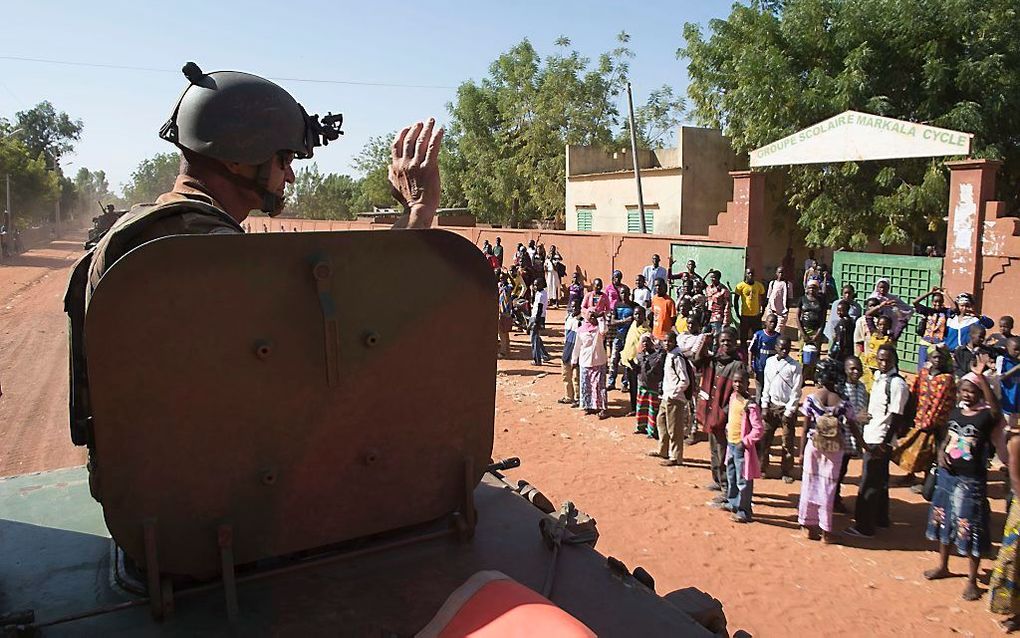 Een Franse militair zwaait naar een groep Malinezen. Foto EPA