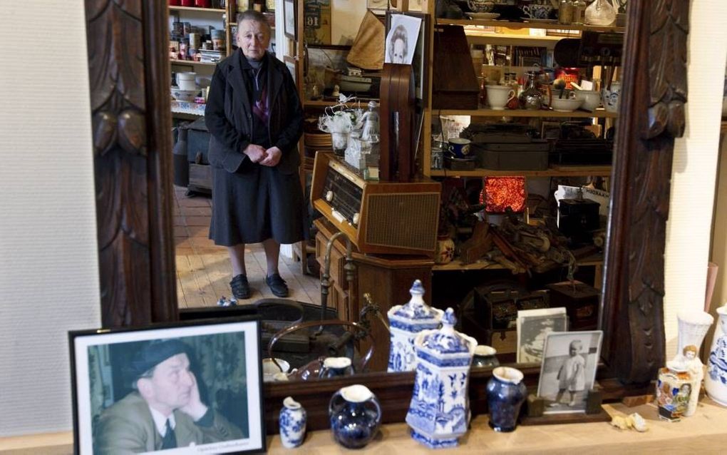 De Werkendamse Grietje Post in haar oudheidkamer. Links een foto van haar overleden broer Hugo. ”Heel bijzonder is dat ik in dezelfde maand als koningin Beatrix ben geboren." Foto RD, Anton Dommerholt