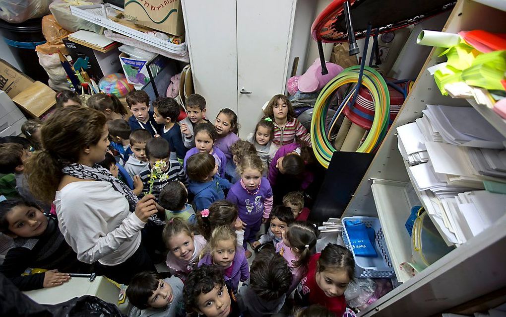 Een lerares zit met haar leerlingen in een schuilkelder in een school in Moshav Beit Zait, ten westen van Jeruzalem. Foto EPA