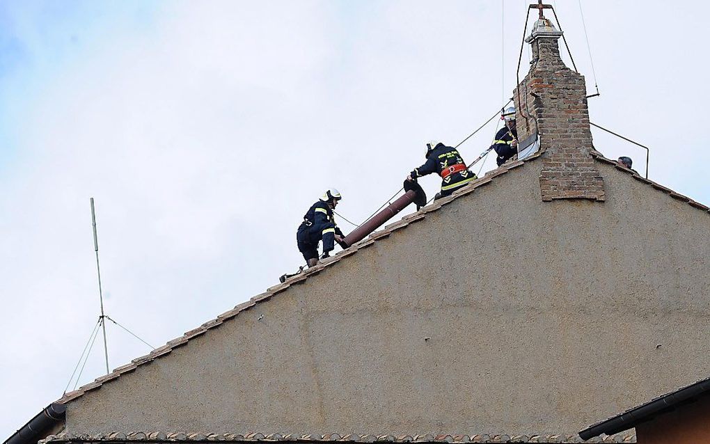 Brandweerlieden installeren een schoorsteen op de Sixtijnse Kapel.  Foto EPA