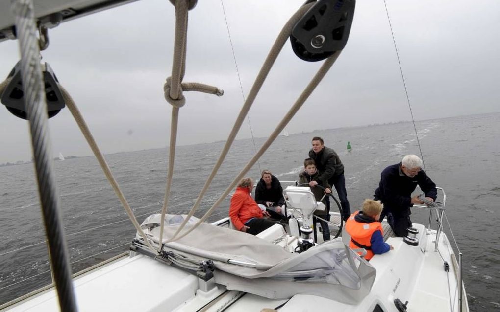 Kees Alberts (r.) laat de jeugd graag kennismaken met de watersport. Terwijl de eigenaar van watersportbedrijf Ottenhome Heeg het zeil van de Explorer one vastzet, ontfermen Eduard Versteeg (19) en Job Verdouw (10) zich over het stuurwiel. Foto Marchje An