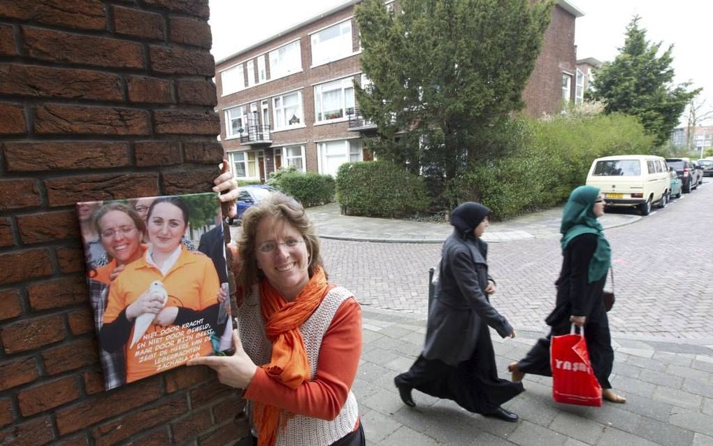 Andrea van den Dool (34) in haar portiek in Rotterdam. In haar hand heeft ze een foto  waarop ze staat afgebeeld samen met Thamar, een vrouw die maanden bij haar in huis woonde en op een dag plotseling verdween. beeld RD, Anton Dommerholt