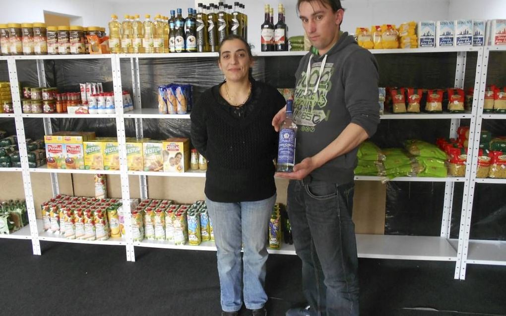 Martinho da Silva en zijn vrouw Sandra Galaio tonen een fles wijn uit Portugal in hun Portugese winkel in Kruiningen. Beeld Linda Otte