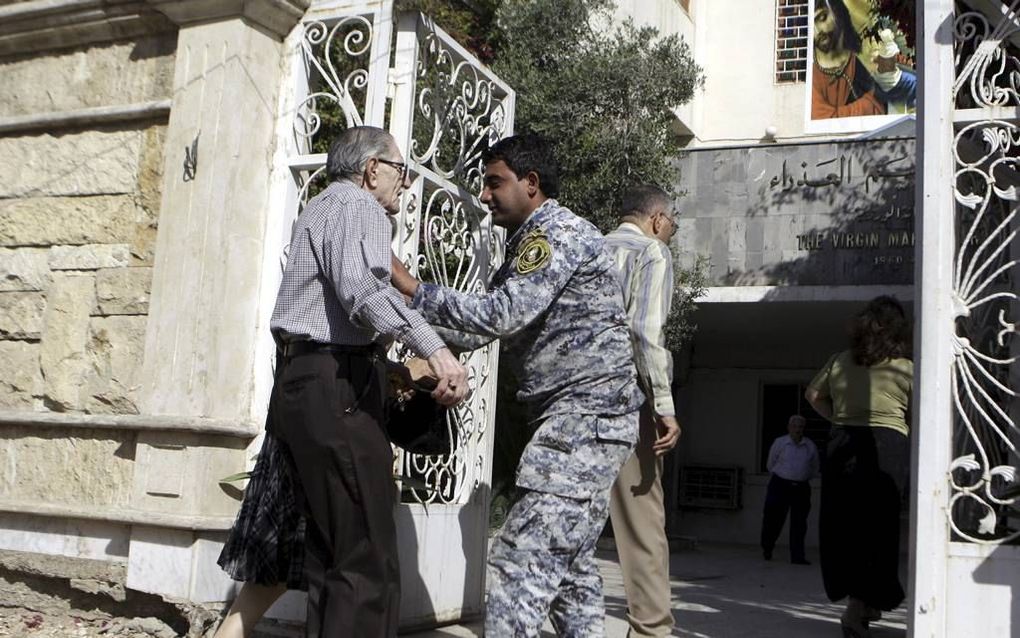 Een Iraakse politieagent controleert een bezoeker van een christelijke kerk in Bagdad.  beeld EPA