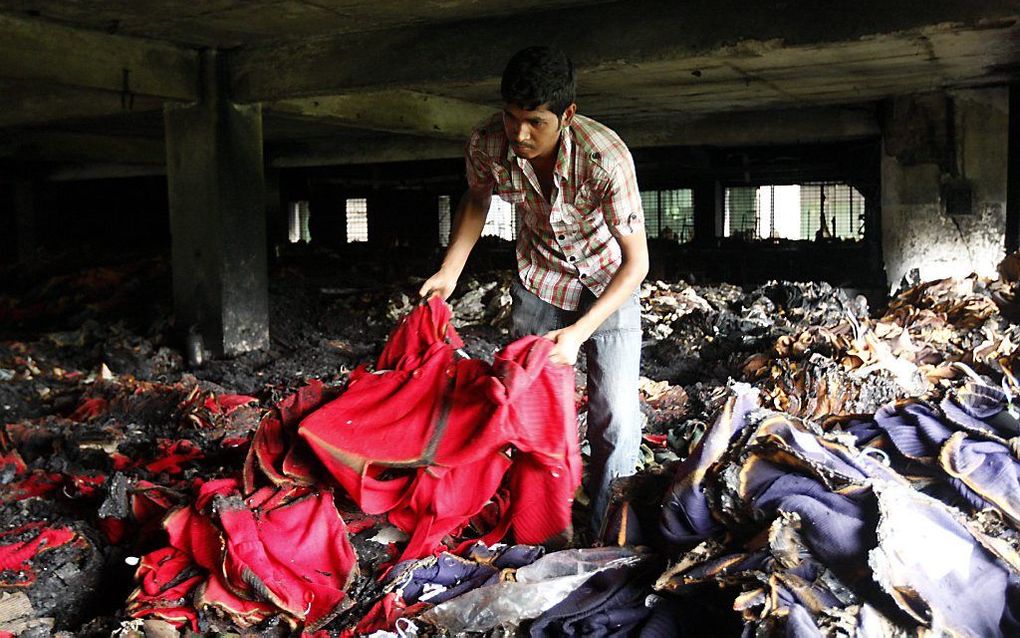 Een man bekijkt de schade na een brand in een kledingfabriek in Dhaka. Foto EPA