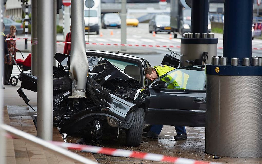 Een politieagent bekijkt het autowrak bij Paleis van Justitie in Den Haag. Foto ANP