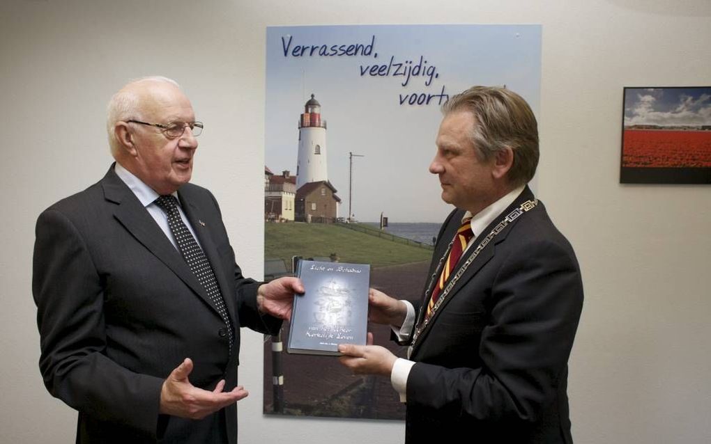 Ds. J. Brons (l.) overhandigde dinsdag een exemplaar van zijn boek over de kerkgeschiedenis van Urk aan P. C. van Maaren, burgemeester van Urk. beeld Dick Vos