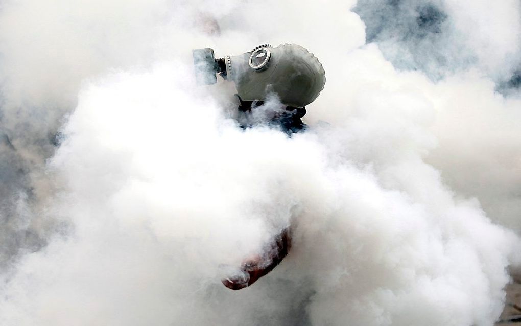 Een Turkse activist met gasmasker staat in een wolk van traangas.  Foto EPA