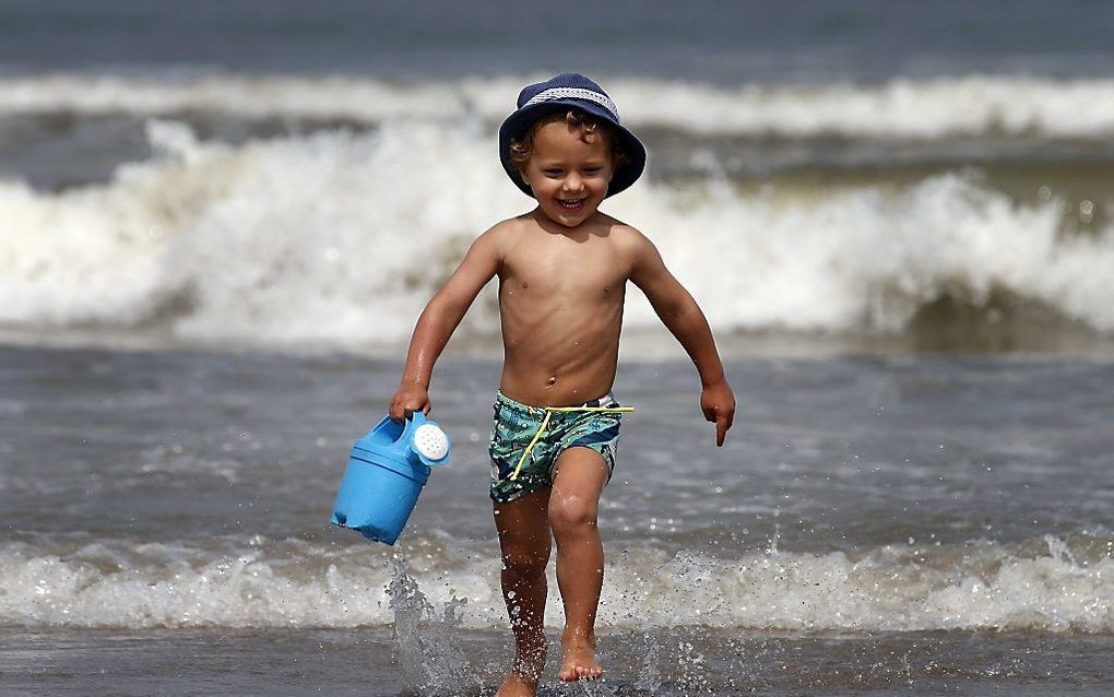 Een jongetje speelt met een gieter tijdens een zomerse dag op het strand van Hoek van Holland. beeld ANP