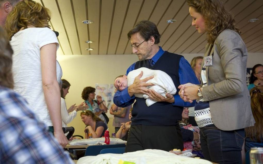 De Amerikaanse kinderarts Harvey Karp met een inmiddels rustige baby op zijn arm, maandag tijdens een workshop in het Tergooi Ziekenhuis in Blaricum. Beeld kbfoto.nl, Kees Boelhouwer