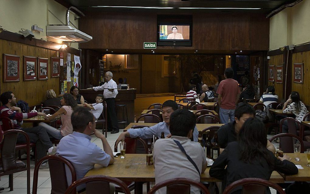 Brazilianen in een bar terwijl op tv de Braziliaanse president Dilma Rousseff het volk toespreekt. Foto EPA