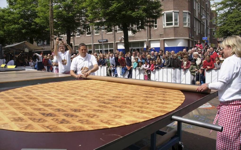 GOUDA. Martien Markus (l.) en Yvette Moerings van de organisatie rollen de folie op voor ’s werelds grootste stroopwafel. beeld Wim de Jongste