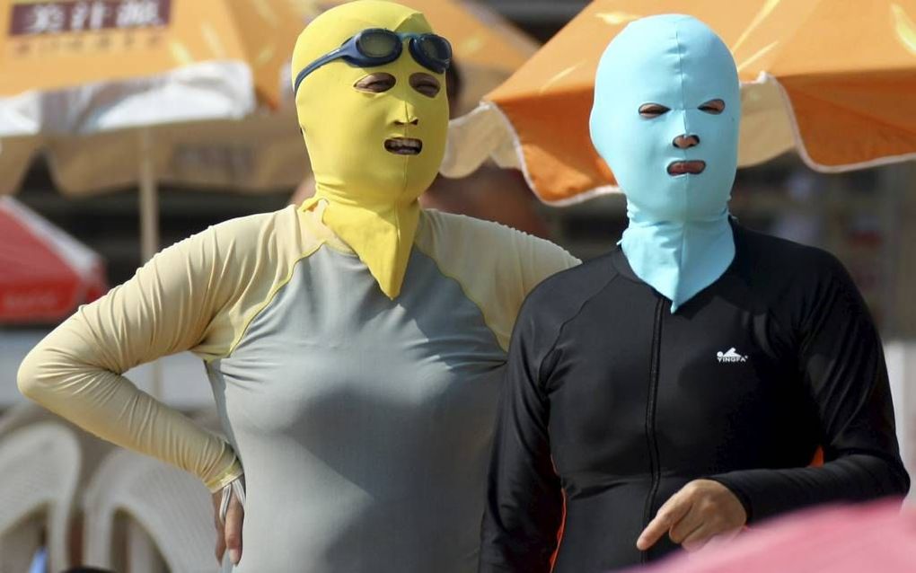 Vrouwen op het strand van Qingdao, gehuld in een facekini, bedoeld om blank te blijven.  beeld EPA