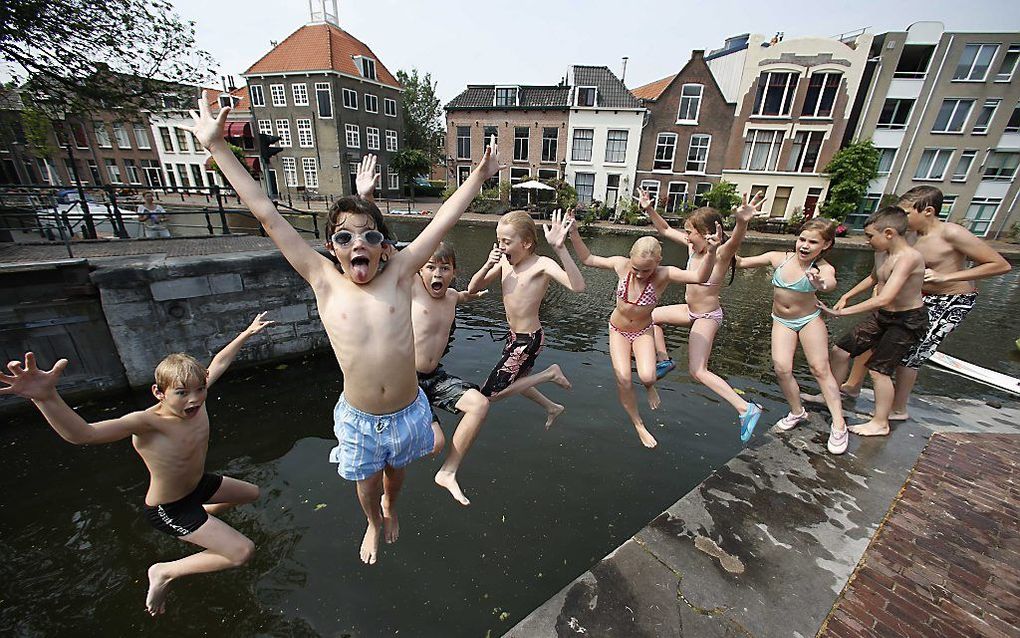 Kinderen springen in het water van de Schie. Met temperaturen rond de dertig graden brengt het water de nodige verkoeling. beeld ANP