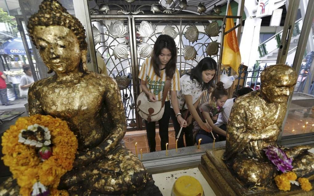 Ouders steken met hun kinderen kaarsen aan in een boeddhistische tempel in de Thaise hoofdstad Bangkok. beeld EPA