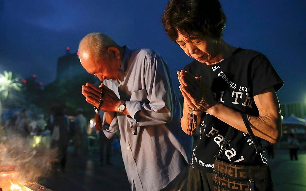 Mensen bidden bij het gedenkteken in het Hiroshima Peace Memorial park. Beeld EPA