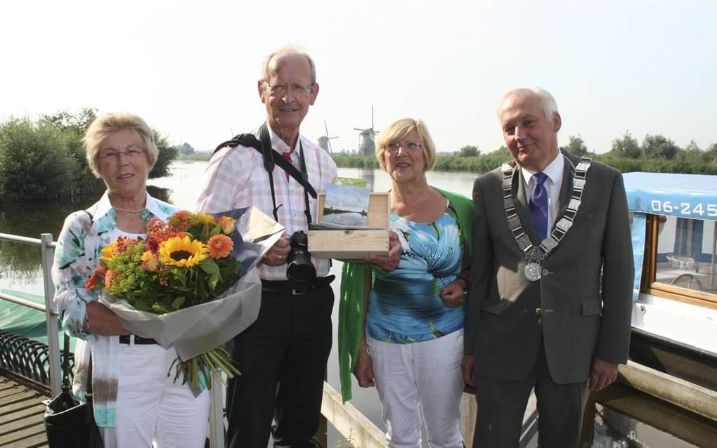 KINDERDIJK. Bij de molens van Kinderdijk verraste burgemeester D. R. van der Borg (r.) van Molenwaard Wim en Ineke Vlasblom (l.) uit Nuenen met een bos bloemen. Wim Vlasblom was de honderdduizendste bezoeker van dit jaar. beeld André Bijl