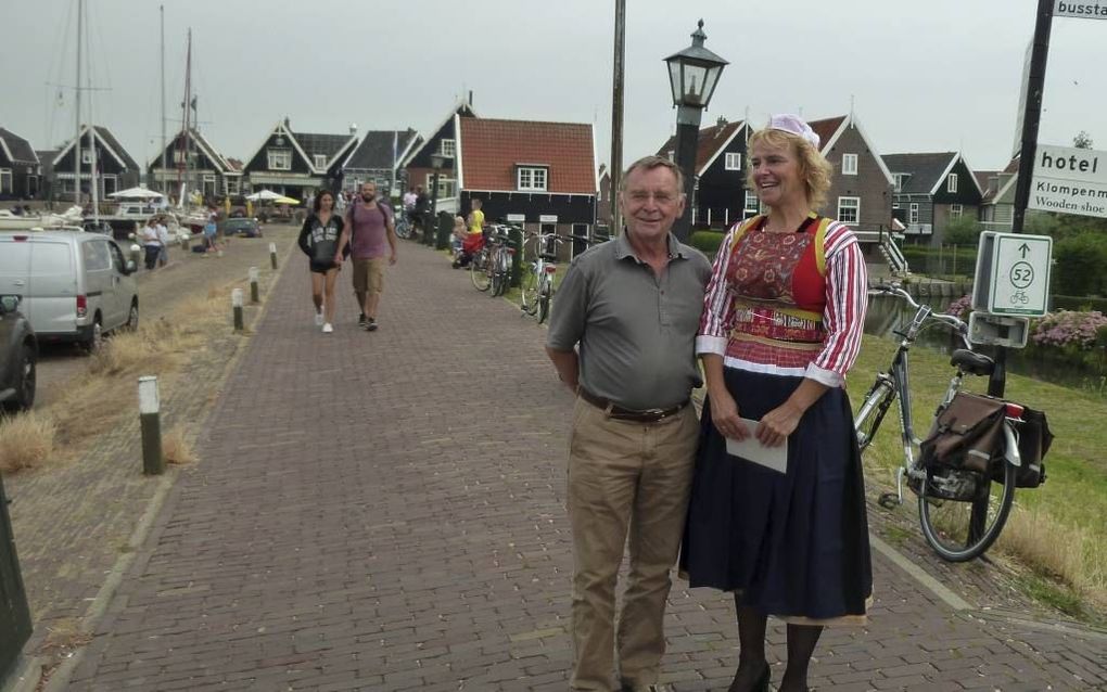 Jan Schild naast een vrouw in Marker klederdracht die toeristen rondleidt bij de haven. Schild leidt een werkgroep die zich verzet tegen nieuwbouw omdat die het dorpsgezicht van Marken zou aantasten. Beeld RD