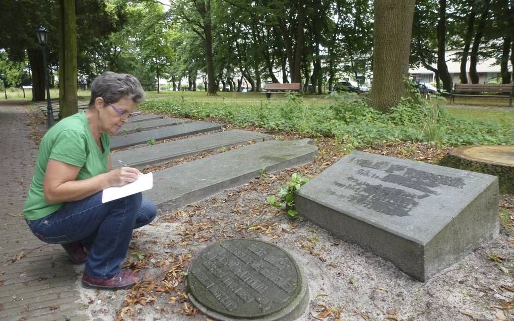 Vrijwilligster Toos de Heus noteert de opschriften op grafstenen van een oude vervallen begraafplaats in Veenendaal. Moeilijk leesbare teksten maakt ze vochtig waardoor ze beter leesbaar worden. beeld Aart Aalbers