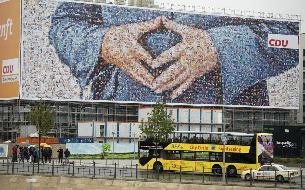 Ooit heeft Merkel besloten hoe ze haar handen wil houden als ze op de foto gaat. De CDU sierde er in Berlijn een gebouw mee. beeld EPA