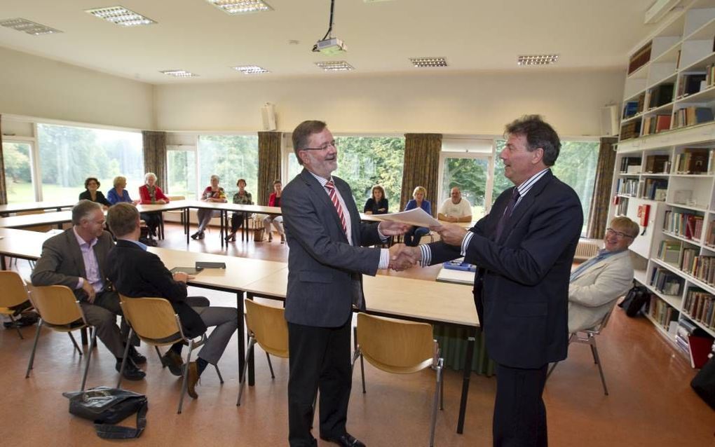 Peter de Haan (r.) van Hogeschool Windesheim in Zwolle overhandigt de nieuwe methode voor de permanente educatie van kerkelijk werkers in de PKN aan dr. A. J. Plaisier. Beeld RD, Anton Dommerholt