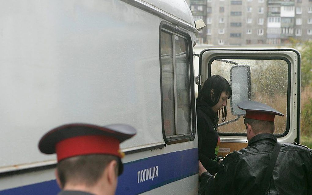 Een activist van Greenpeace stap uit een politiebus bij de rechtbank in Moermansk. Foto ANP