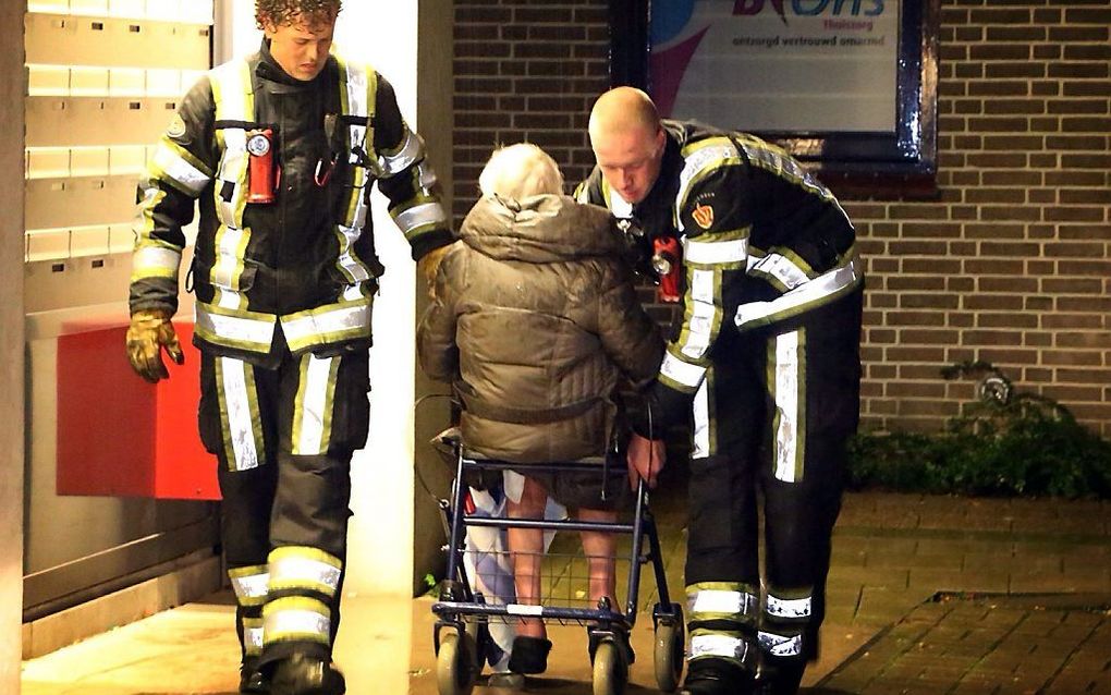 Een bewoonster van seniorenflat De Grote Koppel wordt haar huis uit gehaald in verband met brand. Foto ANP