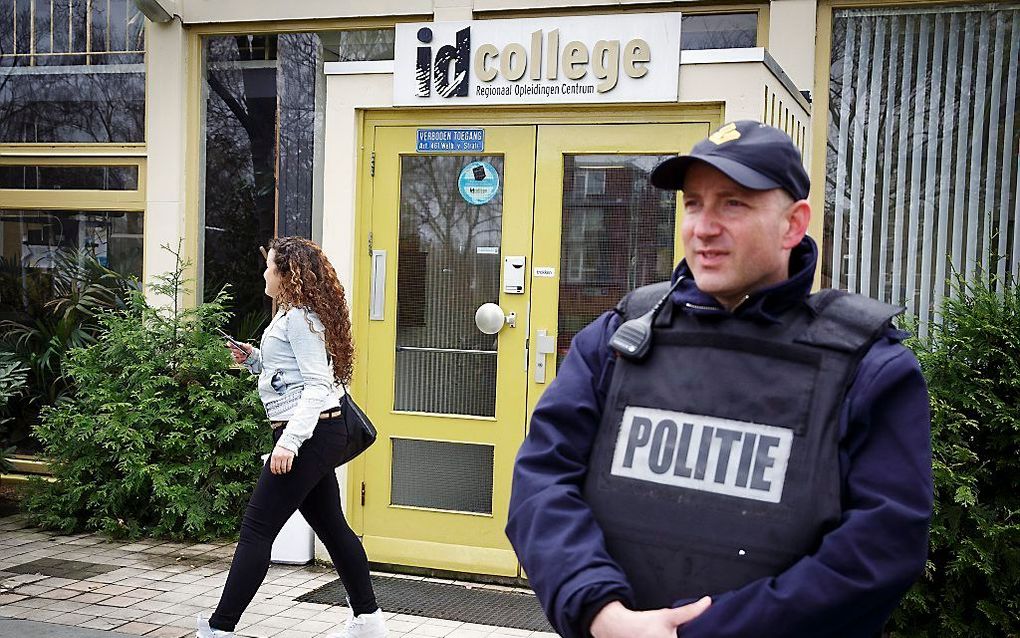 Een politieagent voor het ROC in Leiden, nadat er dreigementen waren geuit. Foto ANP