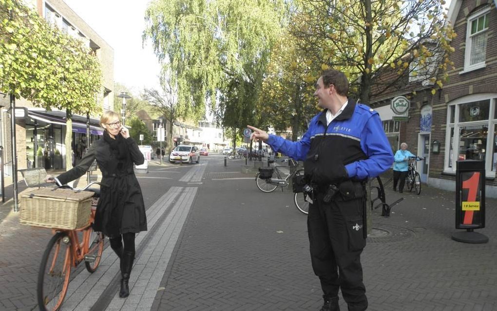 Wijkagent Jelle van Heerikhuize groet in de Dorpsstraat van Ermelo een van zijn volgers. „Omdat mensen mij via Twitter kennen, spreken ze me op straat makkelijker aan.” Foto RD