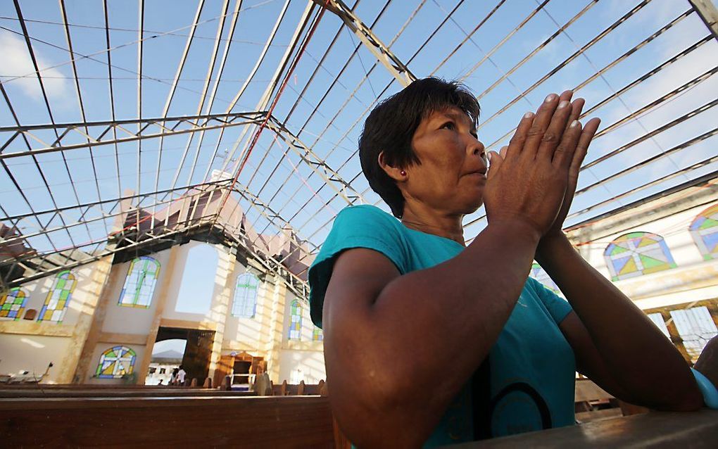 Een vrouw bidt in een kerk zonder dak in de stad Mercedes op het eiland Samar in de Filipijnen. beeld EPA