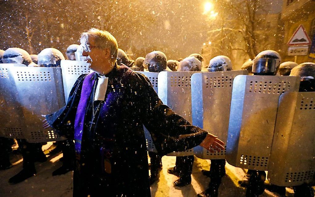 De voorganger van de Lutherse kerk St. Elena in Kiev, probeert demonstranten te bedaren. Foto EPA