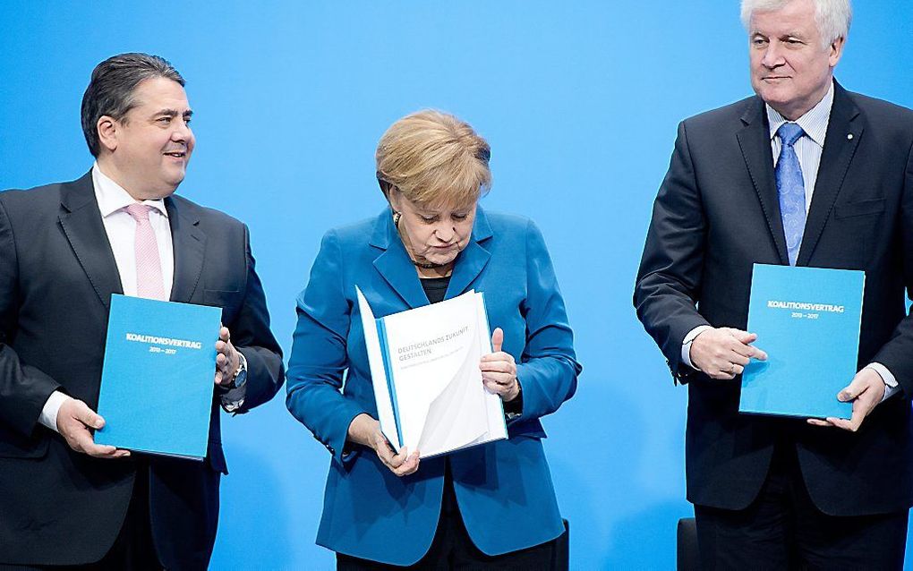 Merkel (m.) en Gabriel (l.) and Seehofer met een exemplaar van het regeerakkoord. beeld EPA