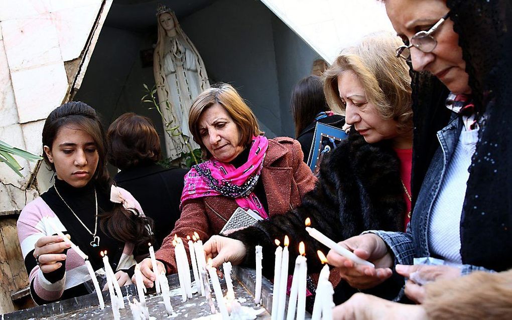 Christenen steken op Eerste Kerstdag een kaarsje aan in een kerk in Bagdad. Foto EPA