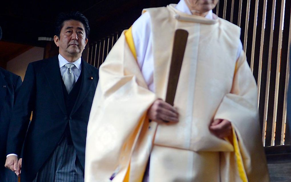 Premier Shinzo Abe (l.) volgt een shintopriester. beeld EPA