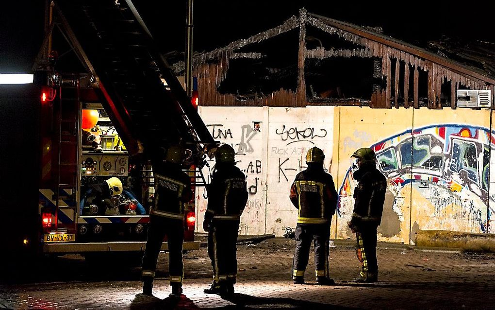 De brandweer in Gouda ruimt op na het blussen van een brand in het clubhuis van een tafeltennisvereniging. Eerder in de nacht werden de brandweermannen tijdens hun werkzaamheden bij de vereniging bekogeld met zwaar vuurwerk, stenen en glas. beeld ANP