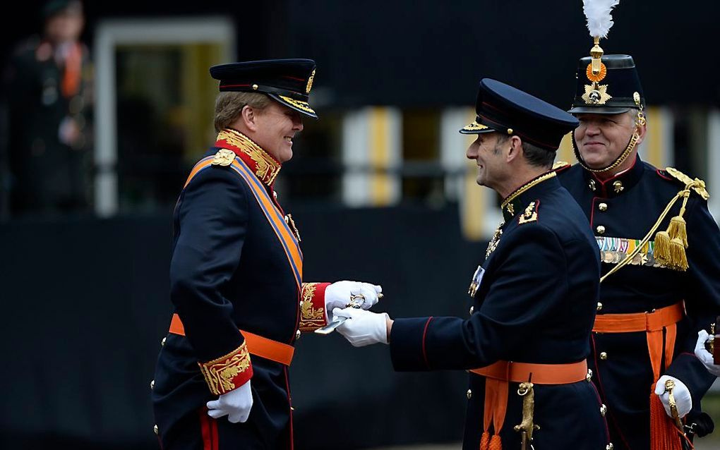 Koning Willem-Alexander zoekt in zijn zak naar een muntje dat hij in ruil voor een sabel wilde overhandigen. Foto ANP