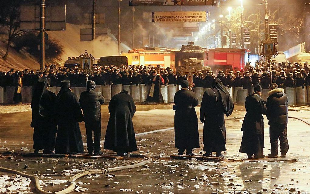 Orthodoxe priesters proberen de broze gevechtsstop tussen de politie en de antiregeringsbetogers te handhaven. beeld EPA