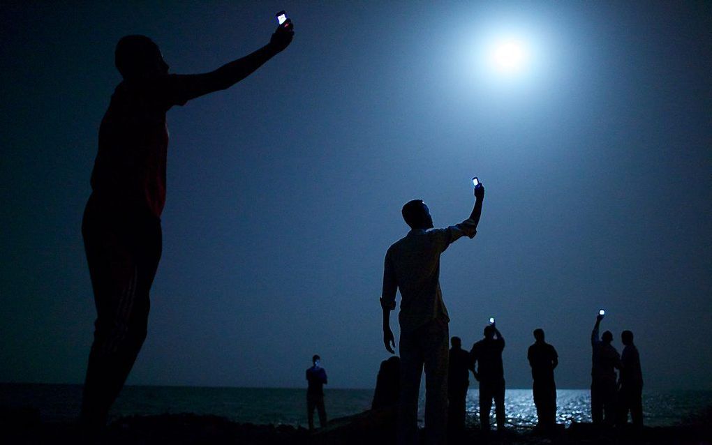 De Amerikaanse fotograaf John Stanmeyer heeft vrijdag de World Press Photo van het jaar 2013 gewonnen. Op de foto staat een groep Afrikaanse migranten in de nacht aan de kust van Djibouti-stad. Ze houden hun telefoons in de lucht in een poging een goedkoo