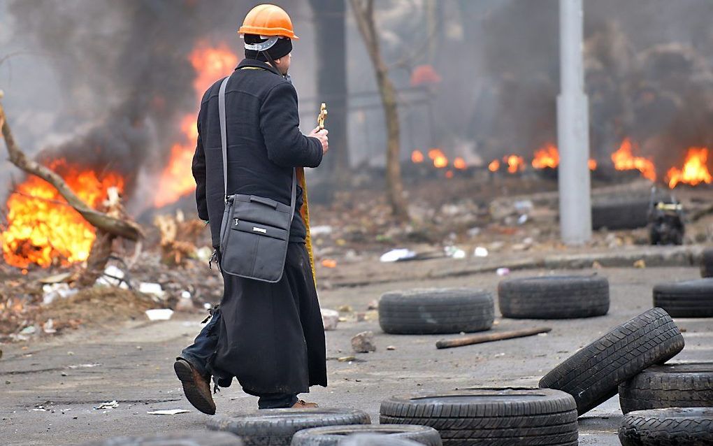 Een priester loopt donderdag 20 februari tussen het strijdgewoel. Beeld AFP