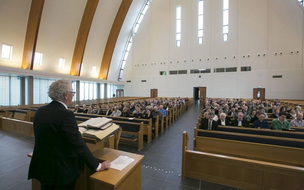 Evangelist Baan (achter katheder) spreekt tijdens de landelijke toerustingsdag evangelisatie van de Gereformeerde Gemeenten. beeld Martin Droog