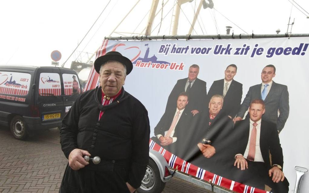 URK. Hart voor Urk-lijsttrekker Jan Koffeman met zijn campagneauto en -reclamebord bij de mistige haven van Urk. beeld RD, Anton Dommerholt