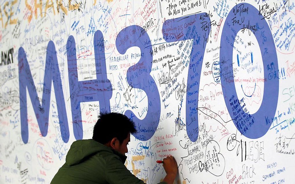 Een man schrijft iets op een herinneringsmuur op de luchthaven van Kuala Lumpur. Foto EPA