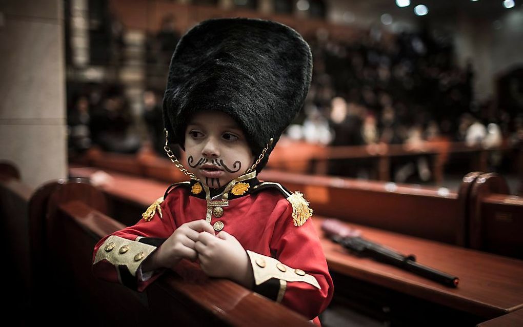 Een ultra-orthodoxe Joodse jongen verkleed als Britse paleiswacht viert zaterdag het Poerimfeest in een synagoge in Bnei Brak, bij Tel Aviv. beeld EPA