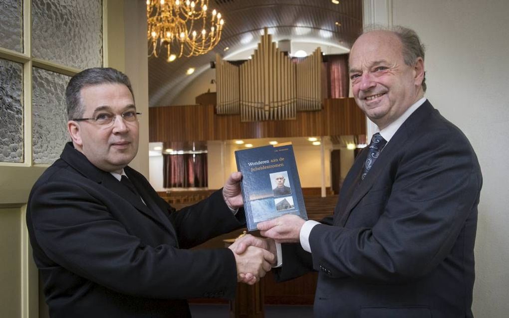 Ds. Zwartbol ontvangt het eerste exemplaar van het boek ”Wonderen aan de Scheldestromen" door Han Vermeulen. beeld Wim van Vossen