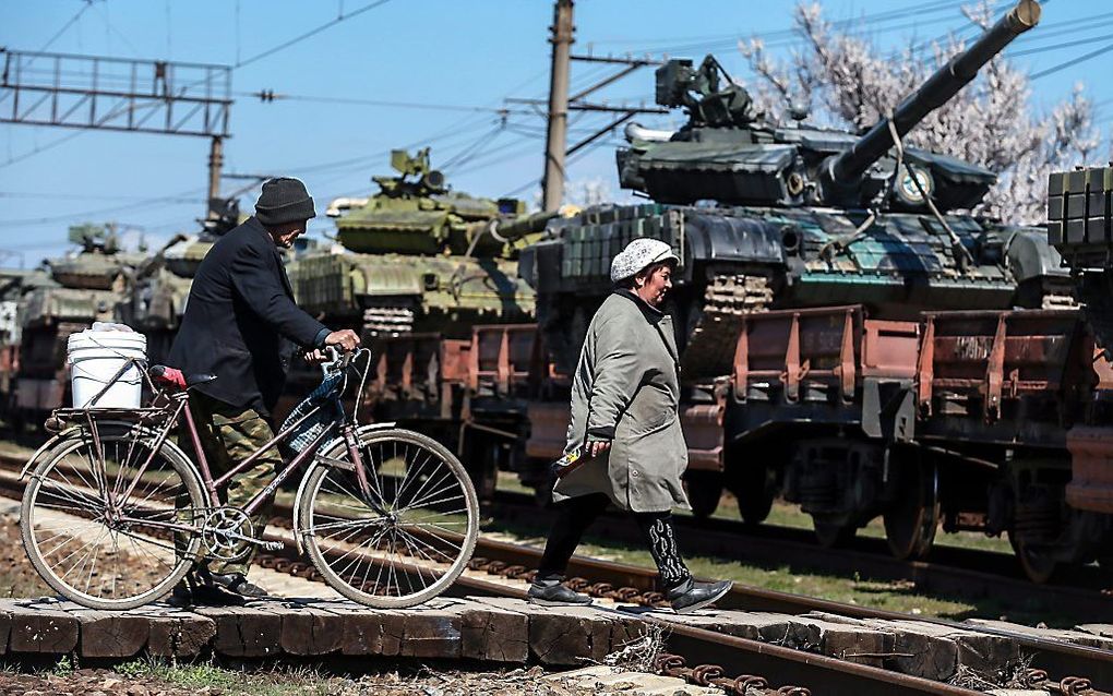 Inwoners van de Krim passeren een transport van tanks. Foto EPA